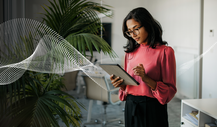 Woman wearing a pink shirt in a hybrid workplace working from a tablet