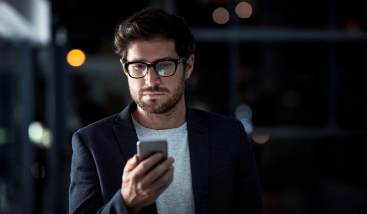 A man types on his phone in the dark because he is using illicit comms