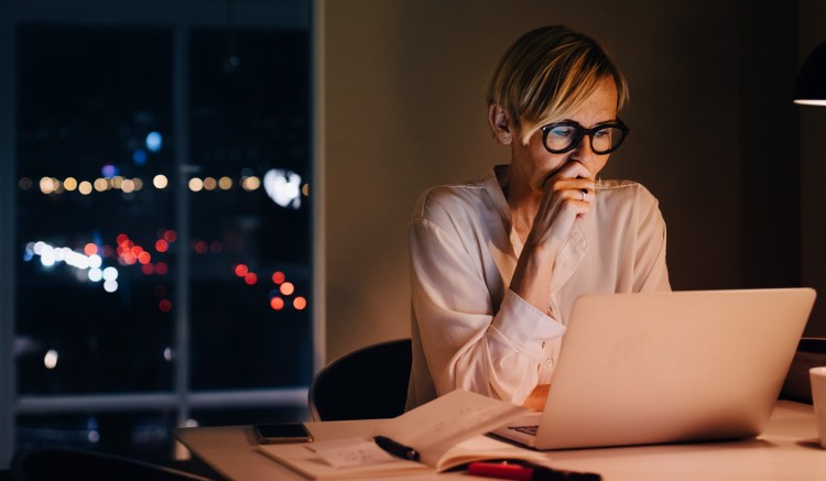 A woman looks at her computer and is stressed by amendments to Regulation SCI