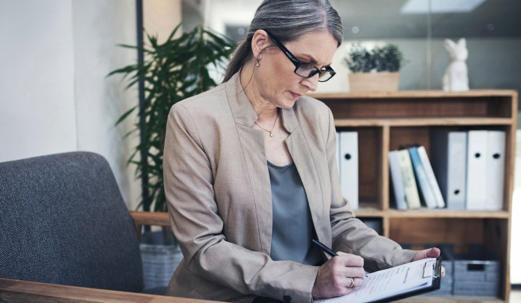 Woman studies a policy management checklist to ensure regulatory compliance.