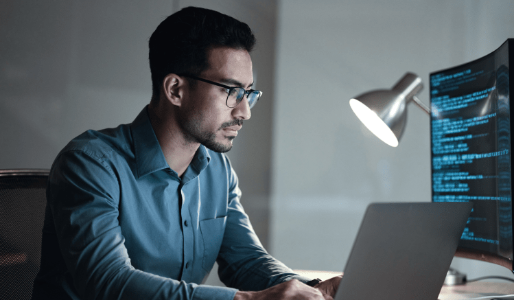 A man in a blue shirt determines how to implement a generative AI platform like ChatGPT into business operations. He researches regulatory rules on generative AI and LLMs.