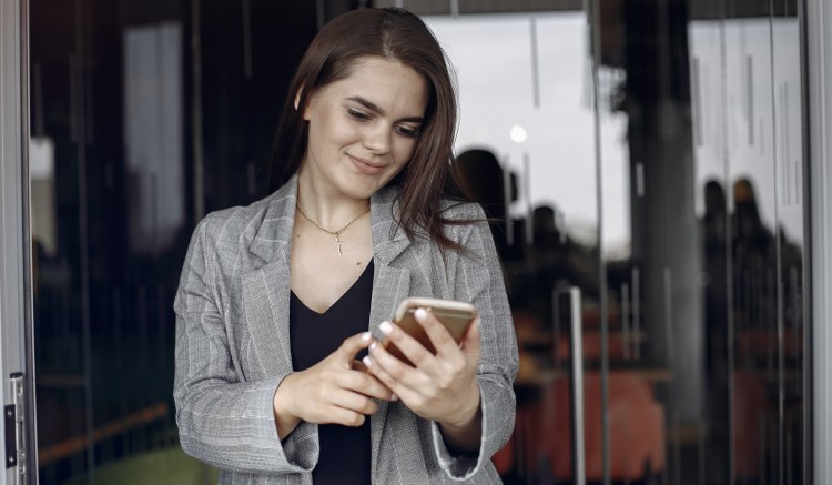 Life sciences employee smiling at her corporate issued mobile device - compliant mobile communications