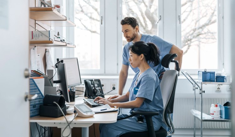 Two healthcare clinicians looking at a computer monitor.