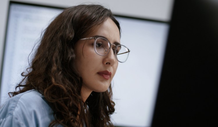 A woman uses AI-enabled tools within risk monitoring processes.